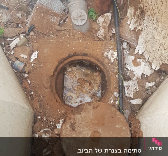 בור ביוב פתוח עם מכסה מונח בצד